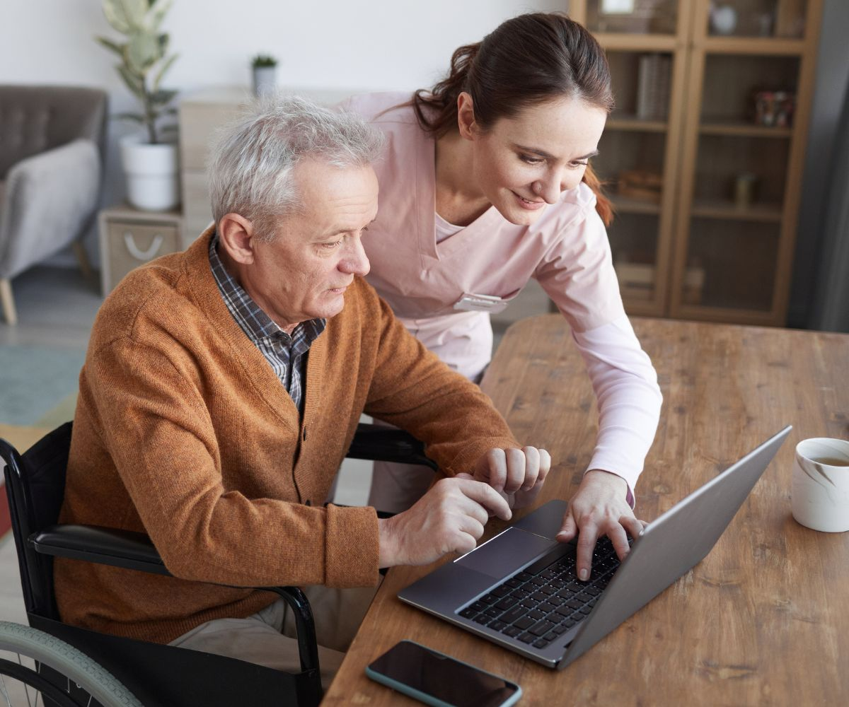 Caregiver helping elderly client with laptop